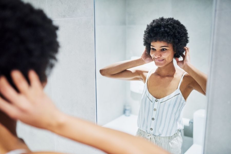 Femme souriante observant sa coiffure pour cheveux fins dans un miroir.