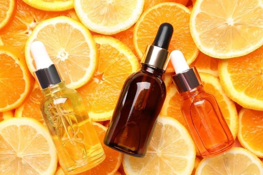 Collection de flacons de sérum vitamine C sur lit d'oranges et citrons