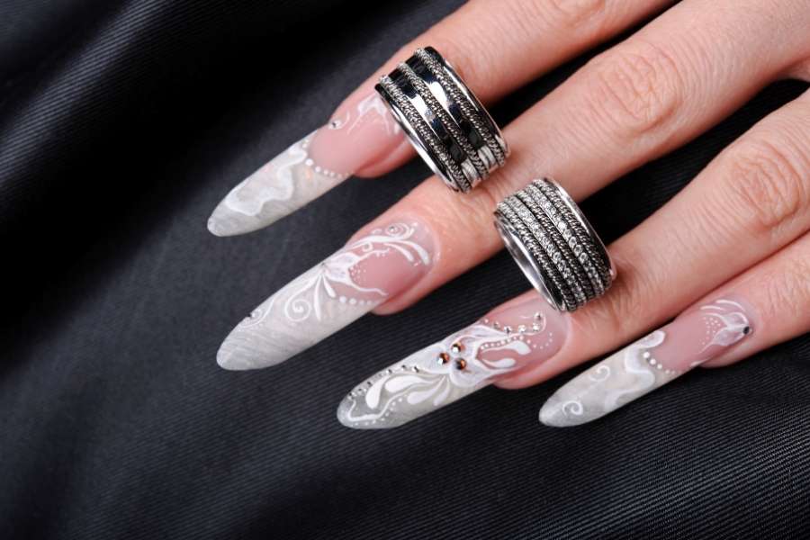 Faux ongles réalistes blancs avec motifs floraux délicats et bagues argentées élégantes